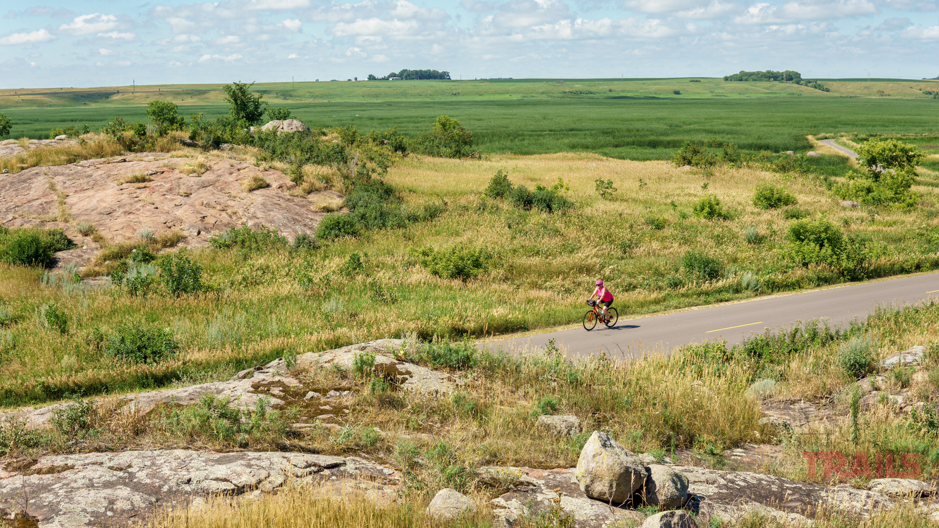 Big Stone National Wildlife Refuge A woman rides her bike on a road past rocky outcroppings