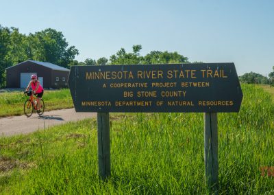 A woman rides her bike on a trail in the summer