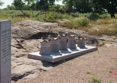 A granite art installation and a stone interpretive marker along a bike trail