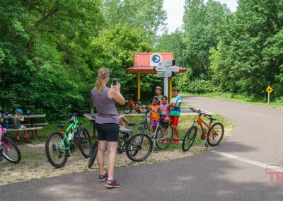 A woman takes a picture of a group of kids at a trail rest area