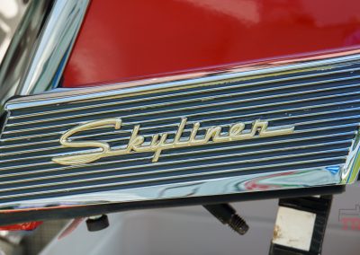 A closeup of the chrome and gold emblem of a Ford Skyliner antique car