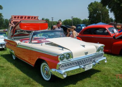 A red and white Ford Skyliner antique car is displayed outside