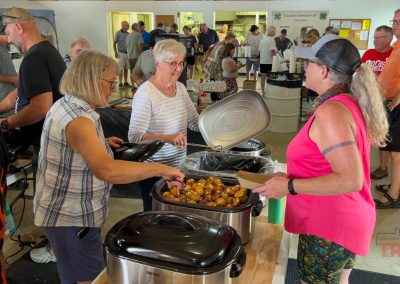 a woman chats with two other women at a lunch line
