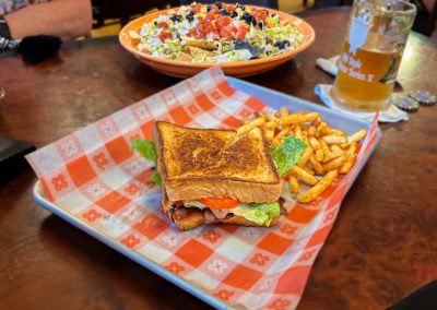 A closeup of a BLT sandwich and nachos on a table