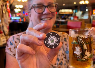 A woman holds up a glass of beer and a poker chip