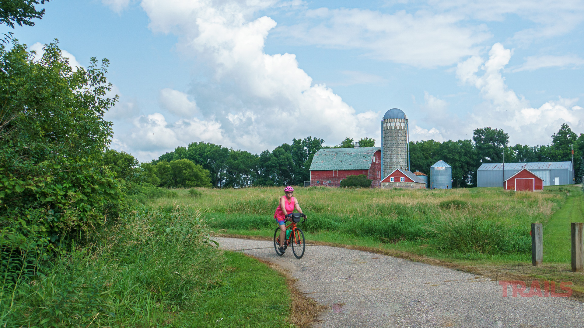 Casey Jones State Trail A woman rides her bike on a paved trail past a red barn and concrete silo