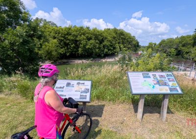 A woman on her bike stops to read interpretive signs