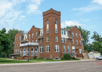 The exterior of a three-tier red brick building with a turret on one corner