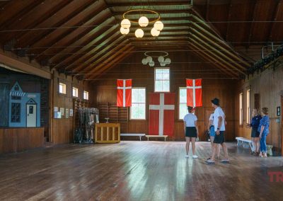 a group of visitors strolls through a historic gym decorated with Danish flags
