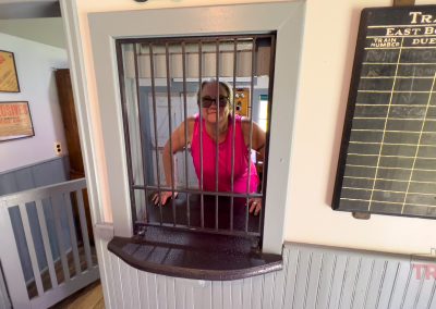 a woman looks out from behind the ticket window in a historic train depot