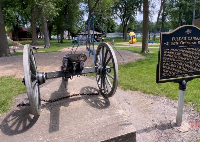 A civil war cannon sits on a concrete pad in a park