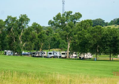 a landscape view of Rvs parked on a grassy field under trees