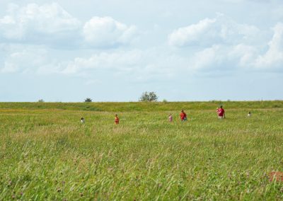 A man, woman and four children walk through a prairie field