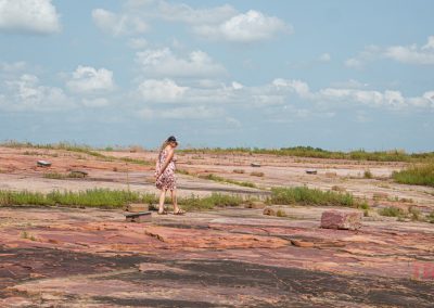 A woman walks on a large plateau made of red rock