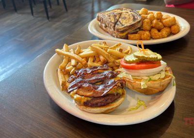 A closeup of a burger and a patty melt on a table