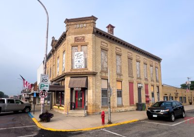 The exterior of a two-story yellow brick building reads 1884 at the top