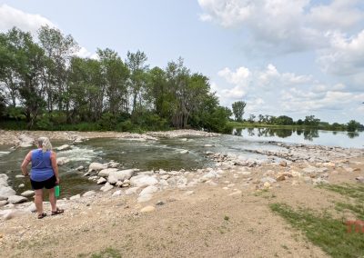 A woman stands by the rushing waters of Lime Lake Dam