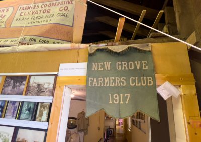 A pendant reading 'New Grove Farmers Club' hangs on the wall in a museum