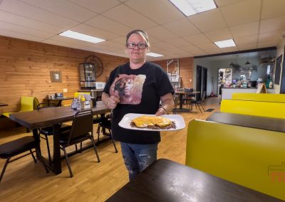 A waitress at a restaurant brings a plate of breakfast food to a table