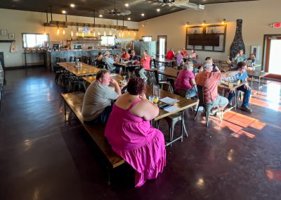 Patrons sit at table on long wooden benches inside a winery