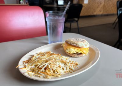 A closeup view of a breakfast sandwich and hashbrowns on a table