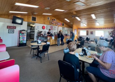 The interior of a diner with wood-clad ceiling, tables and red booths