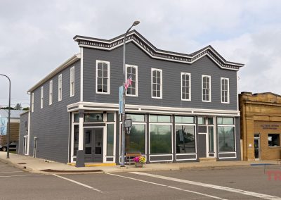 The exterior of a two-story gray wood clad building with large picture windows