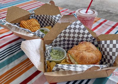 A closeup of two sandwiches and a smoothie on a colorful table cloth