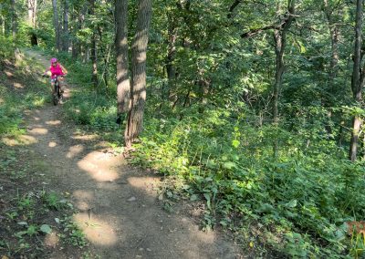 A woman rides a mountain bike through a forest