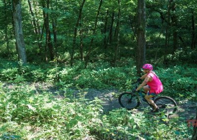 A woman rides a mountain bike through a forest