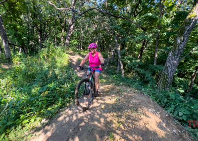 A woman rides a mountain bike through a forest