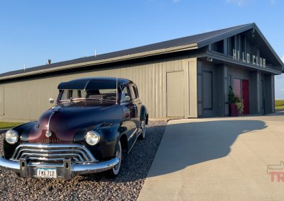 An antique ford sedan is parked in front of a supper club