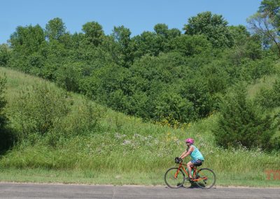 A woman rides her bike on a trail on a sunny day