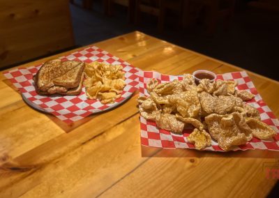 A closeup of fried pork rinds and a sandwich on a table