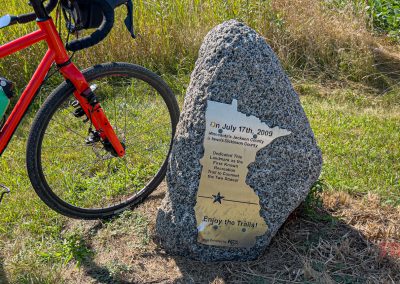 A brass plaque on a rock makes reference to a trail connecting Iowa and Minnesota