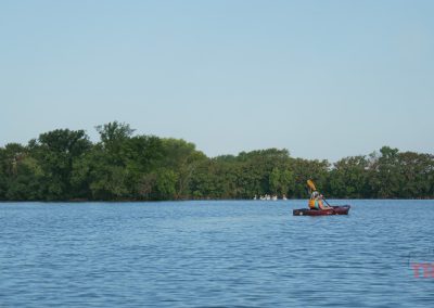 A person in a kayak paddle on a calm lake on a sunny day