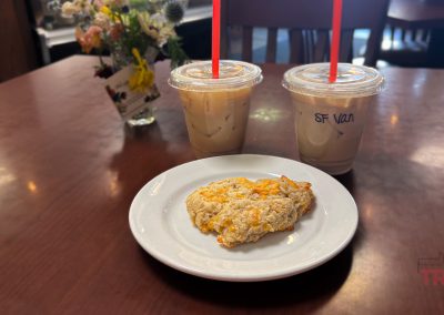 a closeup of a scone and two cold coffee drinks on a table