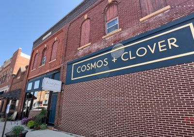 The sign on a red brick building says Cosmos and Clover Boutique