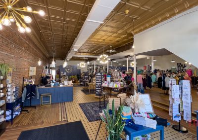 The interior of a boutique with tile floors, brick walls and a tin ceiling