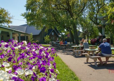 Patrons sit at picnic tables on the grounds of a brewery