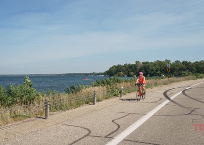 A woman on a bicycle rides along a lake in the summer