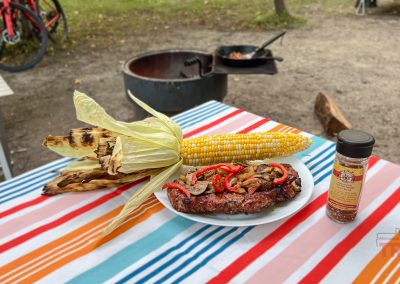 Closeup of a pork steak and an ear of corn on a picnic table