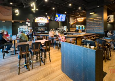 The modern interior of a bar features honey colored wooden floors and black walls