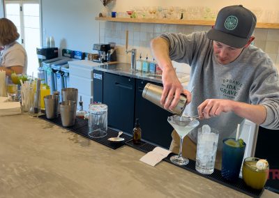 A bartender mixes a pale green drink and strains it into a martini glass
