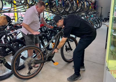 A salesperson points out features of a bicycle to a customer
