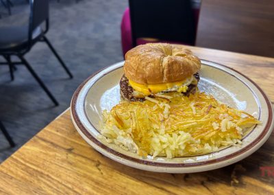 A closeup of a breakfast sandwich with hash browns on a table