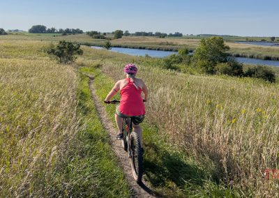 A woman rides a mountain bike through a grassy field at Kensington Rune Stone Park.