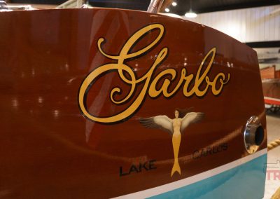 The stern of an antique boat features the name Garbo and a figure of a topless mermaid with wings