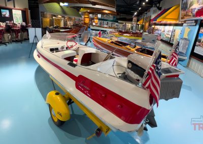 An antique fiberglass boat on display inside of a museum