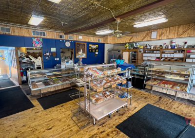 The interior of a bakery with blond wood floors, blue walls and a tin ceiling